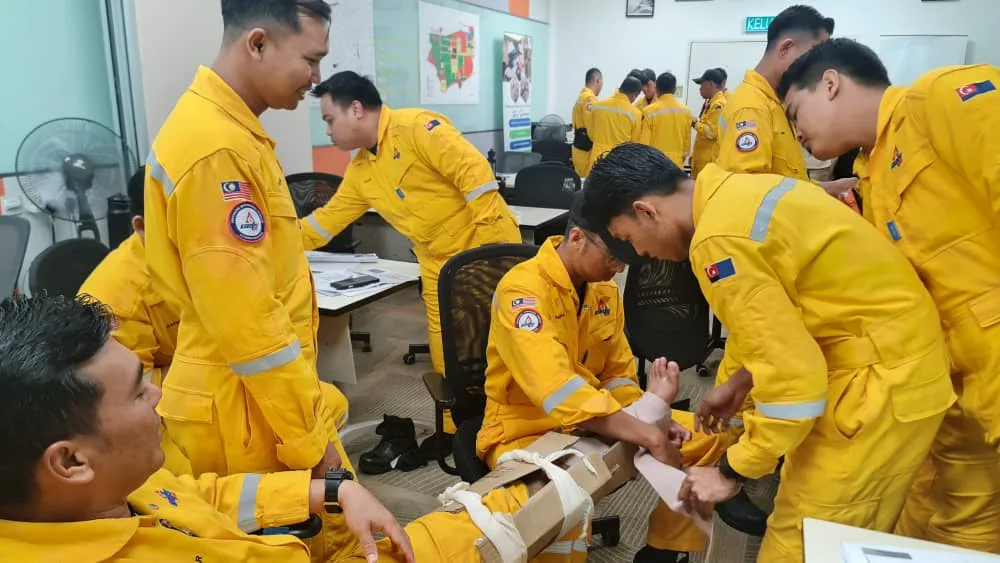 Industrial workers in coveralls practising bandaging and splinting