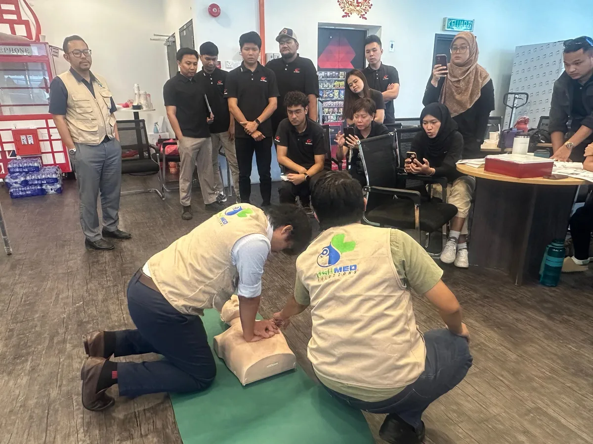 Two OSHMed trainers demonstrating CPR on a manikin while participants watch